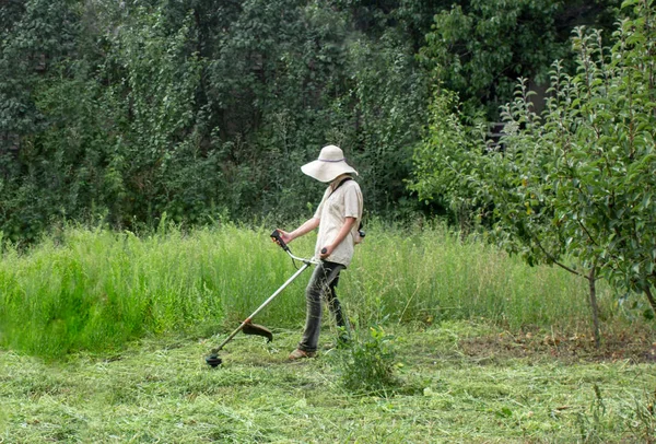 Çim kesme. İş elbiseleri kız bahçede çim mows. Büyük şapka ve gözlük kızı korumak. Kızlar kalıplaşmış değiştirme. Güçlü kadın kavramı
