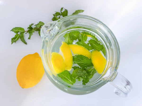 Şeffaf cam sürahide limonlu ve naneli saf su. Sarı limon ve yeşil dal yakında. Yukarıdan bak. Gradyan arkaplan.