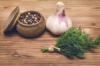 Sarımsak ampul, kahverengi ahşap masa arka plan üzerinde kase ve dereotu yeşil biber bezelye. Organik maddeler.