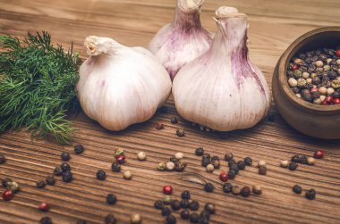 Sarımsak ampul, kahverengi ahşap masa arka plan üzerinde kase ve dereotu yeşil biber bezelye. Organik maddeler.