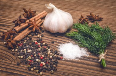 Sarımsak ampul, biber bezelye, tuz, yeşillik dereotu, Yıldız anason ve tarçın kahverengi ahşap masa arka plan üzerinde. Baharat.