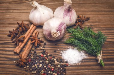 Sarımsak ampul, biber bezelye, tuz, yeşillik dereotu, Yıldız anason ve tarçın kahverengi ahşap masa arka plan üzerinde. Baharat.