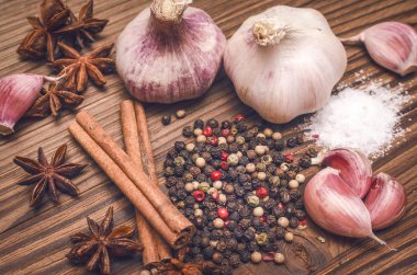 Sarımsak ampul, biber bezelye, tuz, yeşillik dereotu, Yıldız anason ve tarçın kahverengi ahşap masa arka plan üzerinde. Farklı baharatlar.