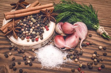 Sarımsak ampul, biber bezelye, tuz, yeşillik dereotu, Yıldız anason ve tarçın kahverengi ahşap masa arka plan üzerinde. Farklı baharatlar.