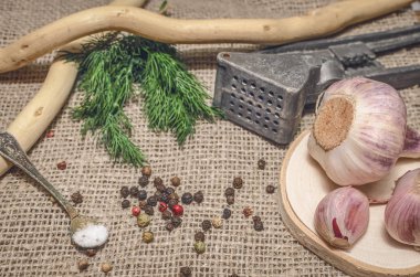 Sarımsak ampul ve karanfil, biber bezelye, tuz, kahverengi ahşap masa arka plan üzerinde yeşil dereotu. Farklı baharatlar. Marine için malzemeler.