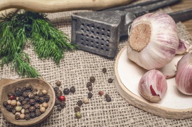 Sarımsak ampul ve karanfil, biber bezelye, tuz, kahverengi ahşap masa arka plan üzerinde yeşil dereotu. Farklı baharatlar. Marine için malzemeler.