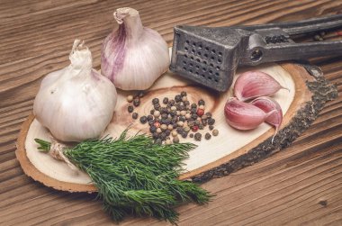 Sarımsak ampul ve karanfil, biber bezelye, tuz, kahverengi ahşap masa arka plan üzerinde yeşil dereotu. Farklı baharatlar. Marine için malzemeler.