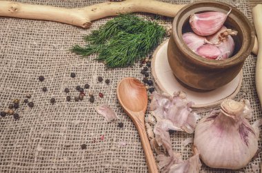 Sarımsak ampul ve karanfil, biber bezelye, tuz, kahverengi ahşap masa arka plan üzerinde yeşil dereotu. Farklı baharatlar. Marine için malzemeler.