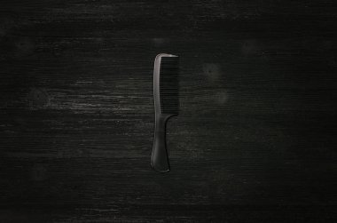 Siyah ahşap arka plan üzerinde izole siyah plastik saç tarağı. 