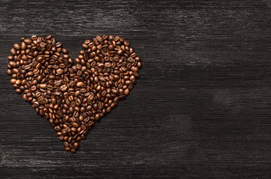 Kahve çekirdekleri kalp şekil form kopya alanı siyah ahşap yüzey zemin üzerine yaptı. Kahve kavramı sevgisi.