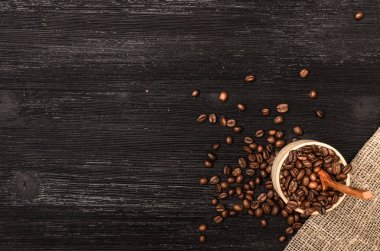 Ahşap pot kopya alanı ile tam kahve ve siyah tablo yüzey zemin üzerine tahta kaşık kahve çekirdekleri dağınık.