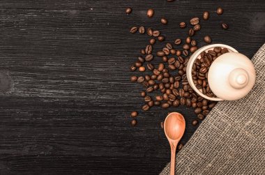 Ahşap pot kopya alanı ile tam kahve ve siyah tablo yüzey zemin üzerine tahta kaşık kahve çekirdekleri dağınık.