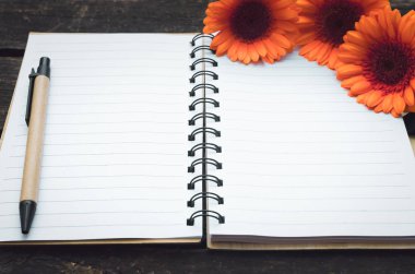 Ahşap arka plan boş sayfa Not defteri ve turuncu gerbera çiçekleri.