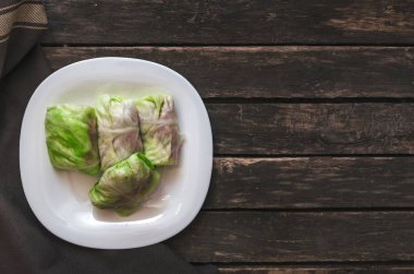 Lahana rulo beyaz tabakta. Çiğ kıyılmış domuz ile sığır yeşil lahana yaprakları.