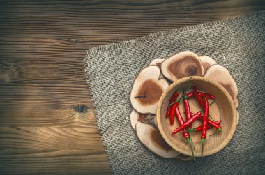 Ahşap plaka çuval bezi çul arka plan üzerinde kırmızı biber biber.