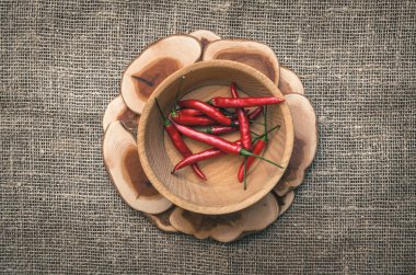 Ahşap plaka çuval bezi çul arka plan üzerinde kırmızı biber biber.