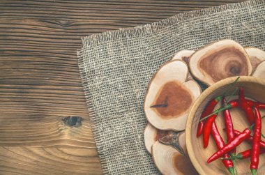 Ahşap plaka çuval bezi çul arka plan üzerinde kırmızı biber biber.