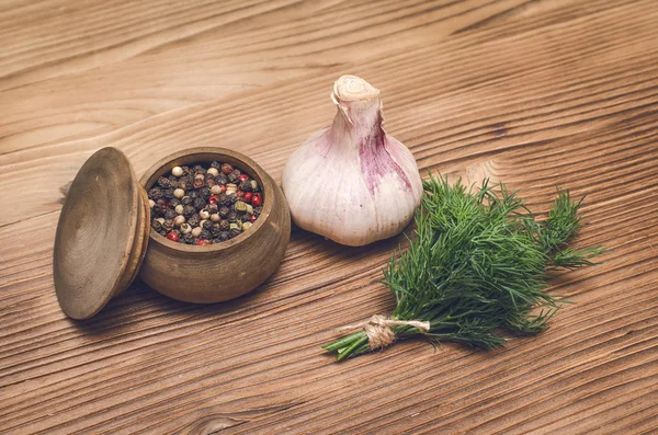 Sarımsak ampul, kahverengi ahşap masa arka plan üzerinde kase ve dereotu yeşil biber bezelye. Organik maddeler.