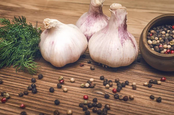 Sarımsak ampul, kahverengi ahşap masa arka plan üzerinde kase ve dereotu yeşil biber bezelye. Organik maddeler.