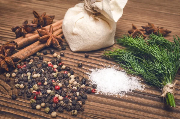 Bezelye, tuz, yeşillik dereotu, Yıldız anason ve tarçın kahverengi ahşap masa arka plan üzerine biber. Baharat.