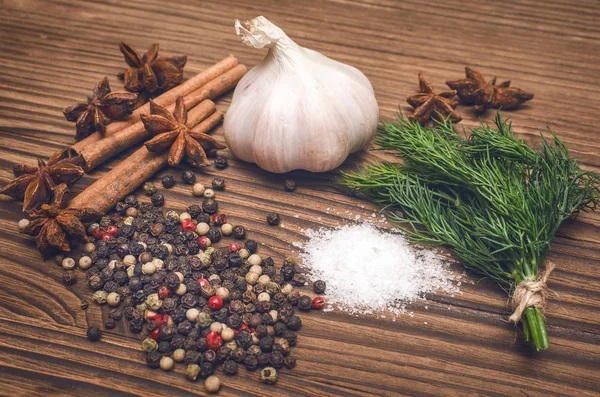 Sarımsak ampul, biber bezelye, tuz, yeşillik dereotu, Yıldız anason ve tarçın kahverengi ahşap masa arka plan üzerinde. Baharat.