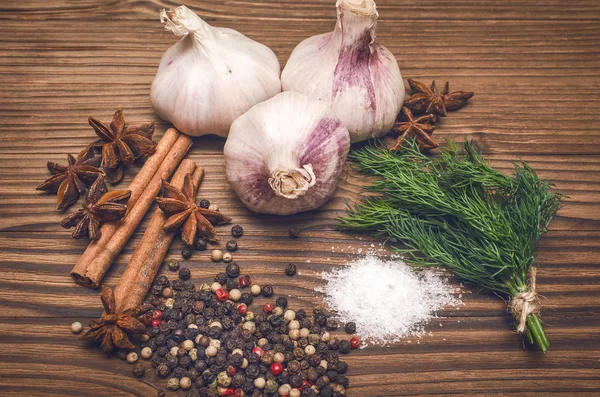 Sarımsak ampul, biber bezelye, tuz, yeşillik dereotu, Yıldız anason ve tarçın kahverengi ahşap masa arka plan üzerinde. Baharat.