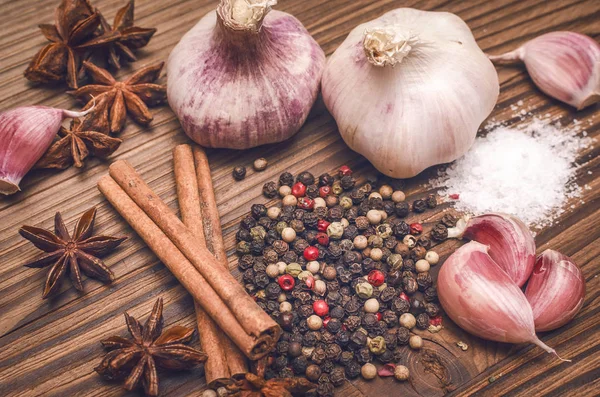 Sarımsak ampul, biber bezelye, tuz, yeşillik dereotu, Yıldız anason ve tarçın kahverengi ahşap masa arka plan üzerinde. Farklı baharatlar.