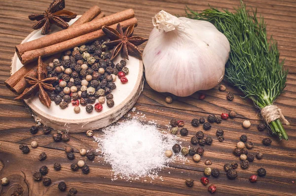 Sarımsak ampul, biber bezelye, tuz, yeşillik dereotu, Yıldız anason ve tarçın kahverengi ahşap masa arka plan üzerinde. Farklı baharatlar.