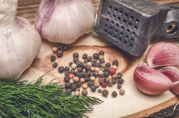 Sarımsak ampul ve karanfil, biber bezelye, tuz, kahverengi ahşap masa arka plan üzerinde yeşil dereotu. Farklı baharatlar. Marine için malzemeler.