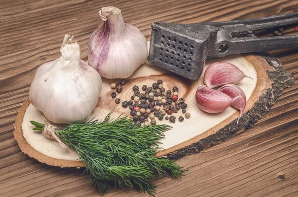 Sarımsak ampul ve karanfil, biber bezelye, tuz, kahverengi ahşap masa arka plan üzerinde yeşil dereotu. Farklı baharatlar. Marine için malzemeler.