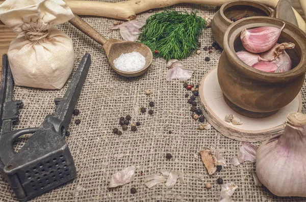 Sarımsak ampul ve karanfil, biber bezelye, tuz, kahverengi ahşap masa arka plan üzerinde yeşil dereotu. Farklı baharatlar. Marine için malzemeler.