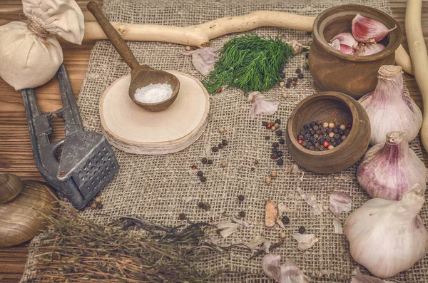 Sarımsak ampul ve karanfil, biber bezelye, tuz, kahverengi ahşap masa arka plan üzerinde yeşil dereotu. Farklı baharatlar. Marine için malzemeler.