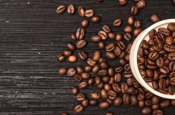 Siyah tablo yüzey zemin üzerine ahşap bir pot kahve çekirdekleri dağınık.