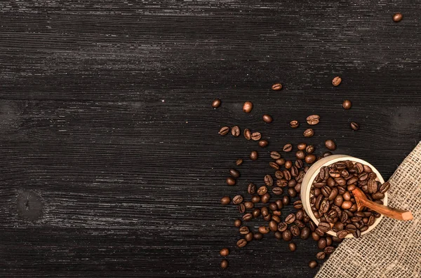 Ahşap pot kopya alanı ile tam kahve ve siyah tablo yüzey zemin üzerine tahta kaşık kahve çekirdekleri dağınık.