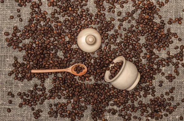 咖啡豆散落在麻布布的背景与木勺和锅 — 图库照片