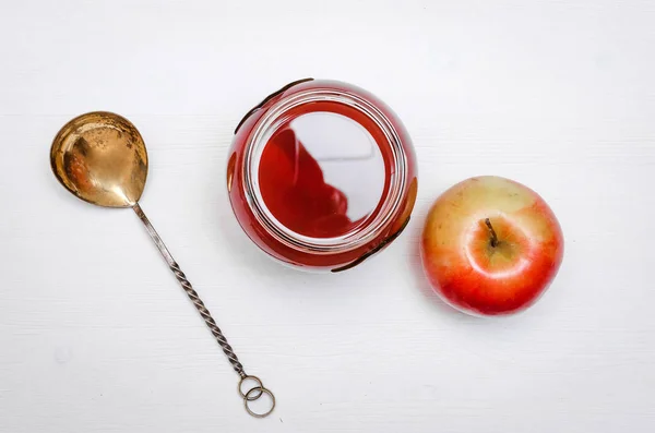 Compote stewed fruit drink in the glass bank with fresh apple on white wooden table.