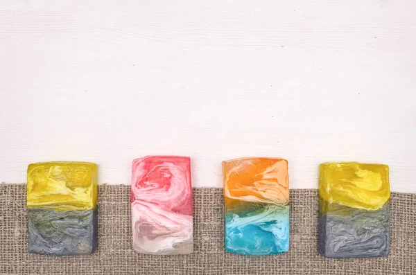 Beyaz ahşap masa arka plan kopya alanı ile üzerine çuval bezi kumaş üzerinde çeşitli katı el yapımı sabun. Banyo aksesuar arka plan.