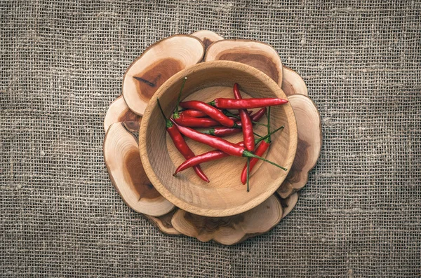 Ahşap plaka çuval bezi çul arka plan üzerinde kırmızı biber biber.