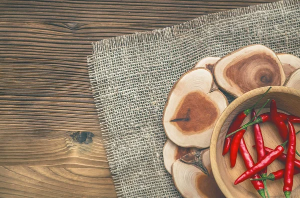Ahşap plaka çuval bezi çul arka plan üzerinde kırmızı biber biber.