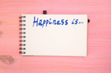 Not Defteri sayfası mor ahşap tahta arka plan üzerinde yazıt mutluluktur.