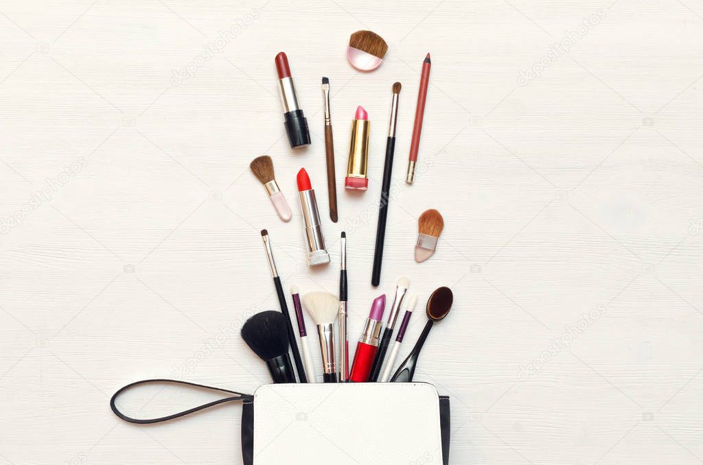 Make up or visage background. Female bag and different make up accessories, brushes, lipstick, and pencils.