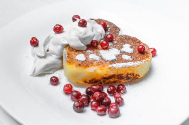 Kızılcık ve pudra şekeri ve ekşi krema Beyaz ahşap masa arka plan üzerinde plaka üzerinde taze pişmiş lor.