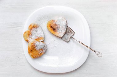 Beyaz ahşap masa arka plan üzerine pudra şekeri ile plaka üzerinde taze pişmiş lor.