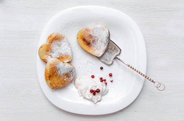 Kızılcık ve pudra şekeri ve ekşi krema Beyaz ahşap masa arka plan üzerinde plaka üzerinde taze pişmiş lor.