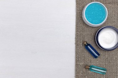 Spa aromaterapi kavramı arka plan kopya alanı, düz ile yatıyordu. Kavanoz ve uçucu yağ beyaz ahşap masa arka plan üzerinde yüz kremi fırçalayın.