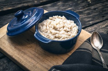 Koyu ahşap arka plan üzerinde mavi seramik tencerede arpa yulaf lapası. Sağlıklı kahvaltı.
