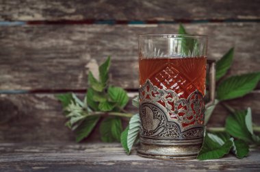 Ahşap masa arka plan üzerinde ahududu yaprakları ile yeşil çay.