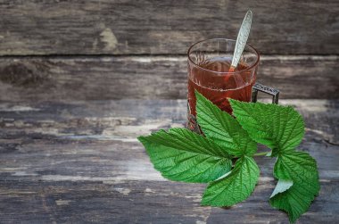 Ahşap masa arka plan üzerinde ahududu yaprakları ile yeşil çay.