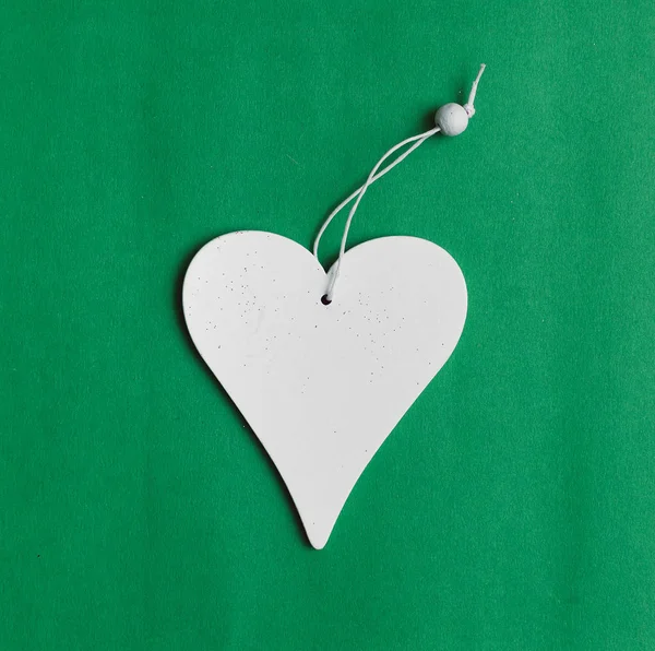 White heart shape toy with copy space isolated on green background.