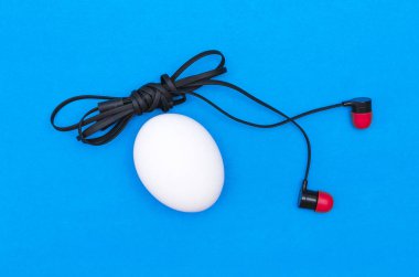 Tavuk yumurta ve üzerinde mavi arka plan izole kulaklık. Abtract fotoğraf.